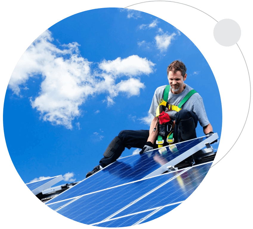 A man is holding a baby on the roof of a solar panel.