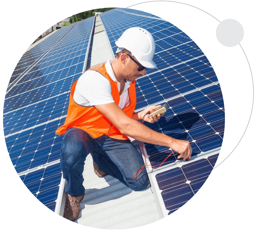 A man in an orange vest and hard hat working on solar panels.