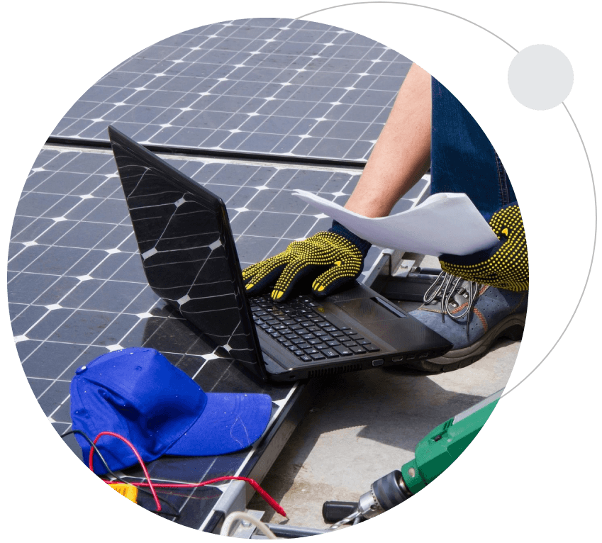 A person working on a laptop near some solar panels.